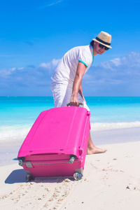 年轻的旅行者，与他的行李在一个热带的海滩上