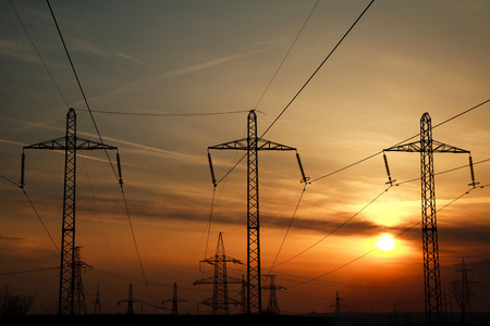 高功率电线路杆塔在戏剧性的日落背景