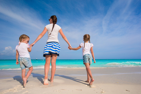 年轻快乐的妈妈和她可爱的女儿，在异国风情的沙滩上阳光明媚的日子开心
