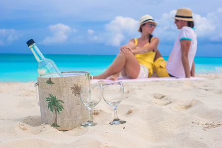 一瓶酒和两杯背景幸福的夫妇在海滩