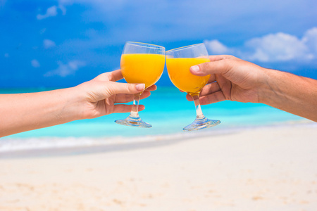 两个手拿眼镜与橙汁背景蓝色天空