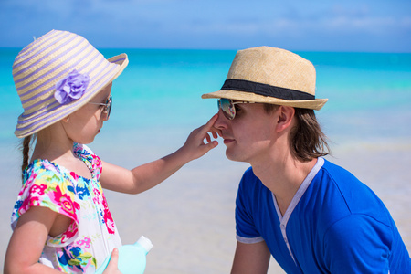 petite fille enduisant de crme de protection solaire de son pap