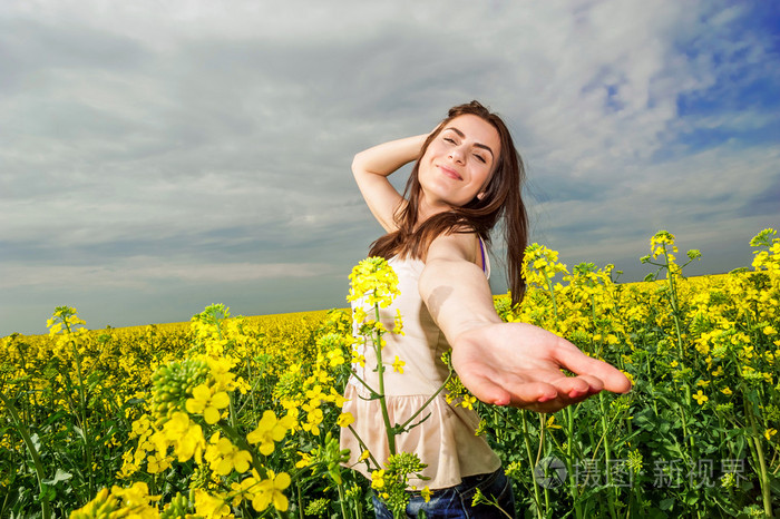 伸手去拿相机在黄色油菜花田的女人的画像
