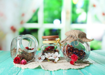 各式各样的草药和茶在玻璃罐里的木桌前，在明亮的背景上