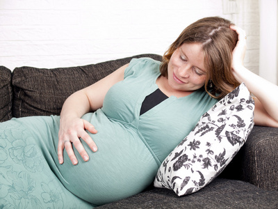 怀孕的年轻女子在沙发上休息