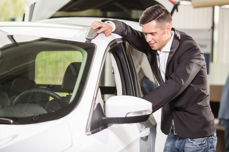 英俊的年轻男人,站在旁边看里面的红色跑车照片