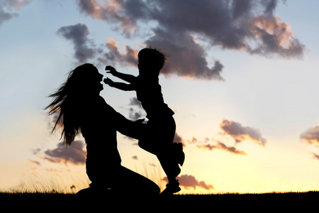 Silhouette des Kindes ausgefhrt, um die Mutter bei Sonnenunterg