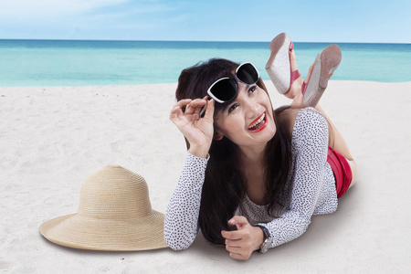 美丽的亚洲女孩躺在海滩上