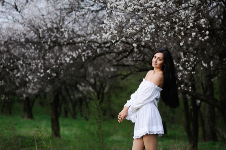 在花的背景上的白色连衣裙的女孩