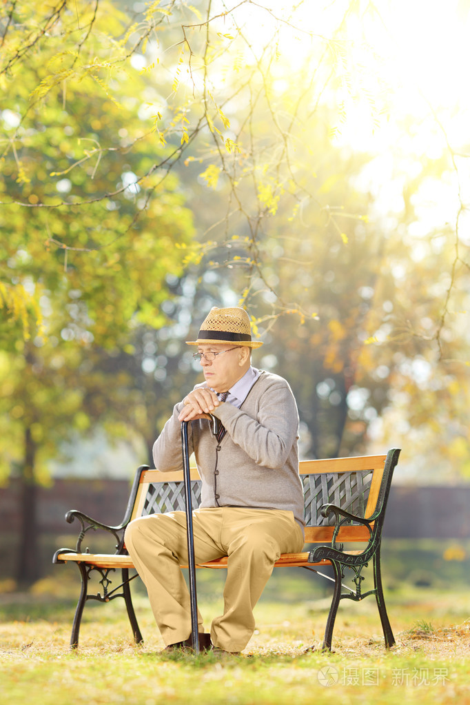拄着拐杖在长椅上的老绅士