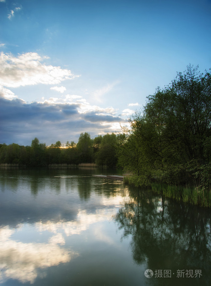 在平静的湖面水域反映了充满活力的夏天日落景色