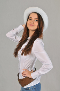 女孩弯背在白色的衬衫，用一只手，包含在他头上的白帽子