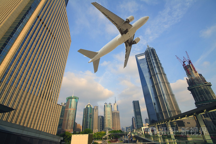 飞机在飞越的现代城市建筑