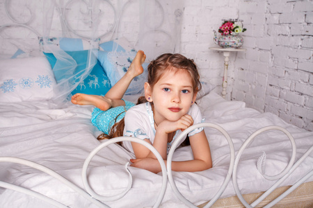 漂亮的小女孩坐在她的卧室里的白色毯子上