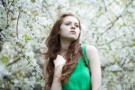 年轻漂亮的女孩站在开花的树木在春天 gard 附近