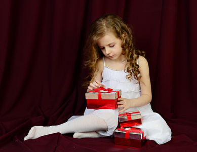 美丽的姑娘坐在红色背景与礼物