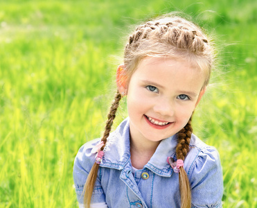 可爱微笑小女孩在草地上的肖像
