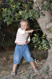 快乐的年轻女孩，站在附近一棵树在花园里