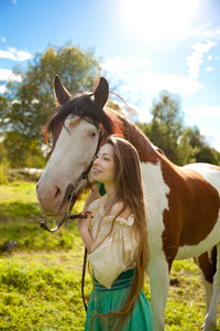 美丽的女子和一匹马在该字段中。在农场上的女孩