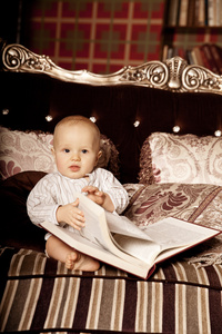 小的孩子在内地读一本书。在微笑的婴儿