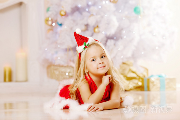 美圣诞老人附近圣诞树上的小女孩。快乐的女孩无线