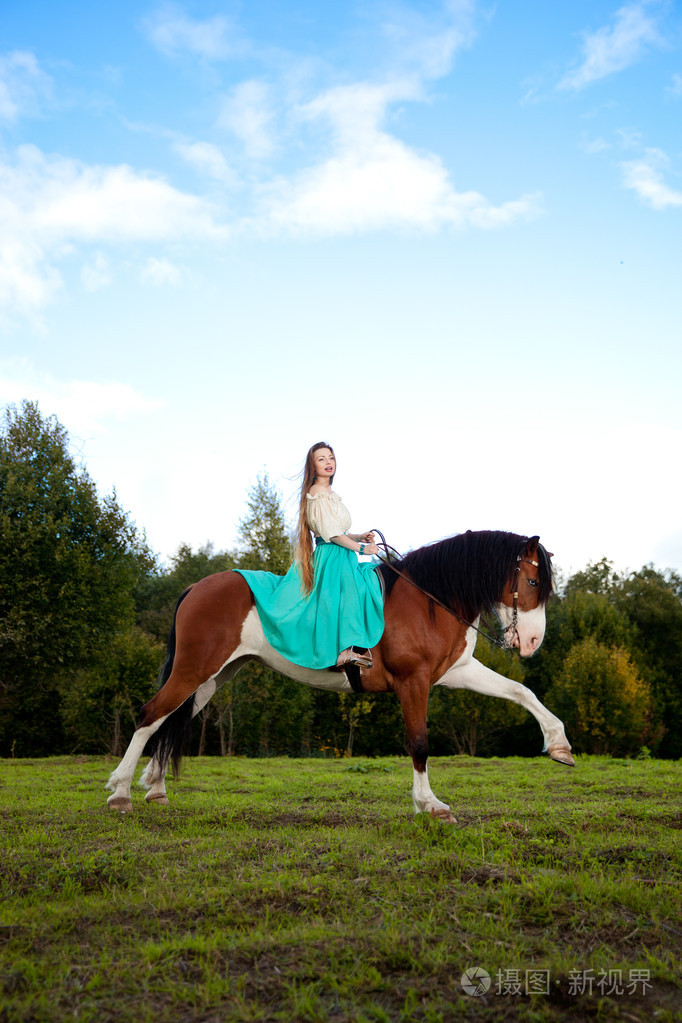 美丽的女子和一匹马在该字段中.在农场上的女孩