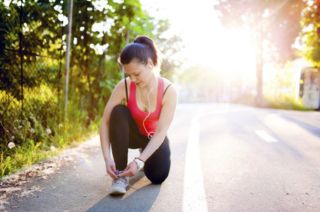 微笑的女子赛跑运动员准备在城市公园中的马拉松 绑鞋带和准备的肖像