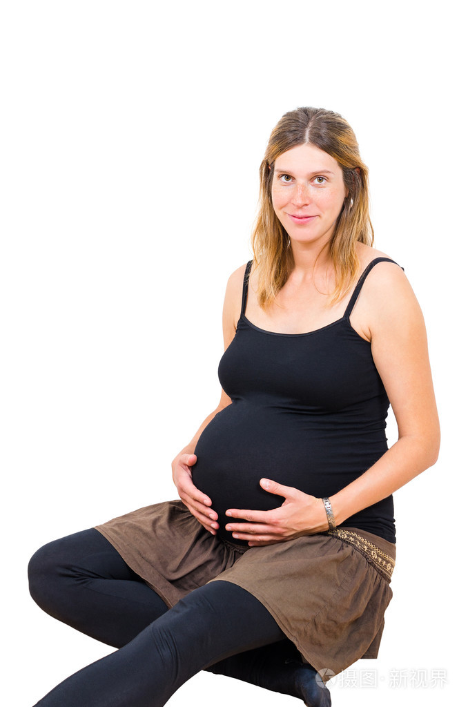 年轻孕妇坐着,看着相机孤立