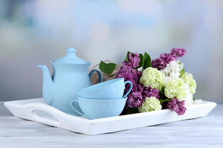 组成与茶具和对上的纸盒，木桌前，在明亮的背景上美丽的春天的花束