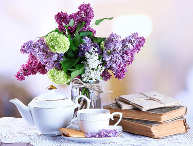 组成与茶壶 杯子和美丽的春天鲜花插在花瓶里，木制的桌子，在明亮的背景上