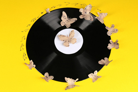 与纸蝴蝶，在黄色背景上的老黑胶唱片。