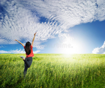 快乐的女人在草地和蓝天上跳跃