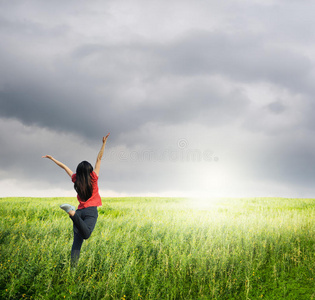 快乐的女人在草地和雨云中跳跃