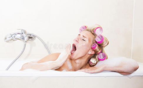 浴缸里拿着卷发器的女人打呵欠