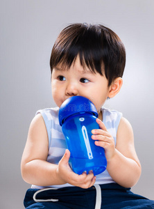 男婴拿着水瓶喝水，然后把视线移开