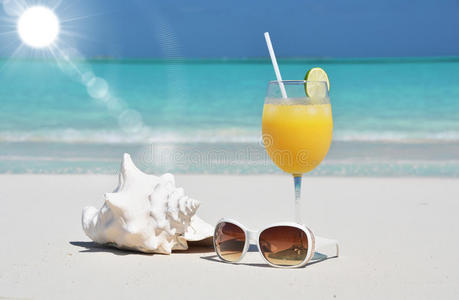 沙滩上的橙汁和太阳镜