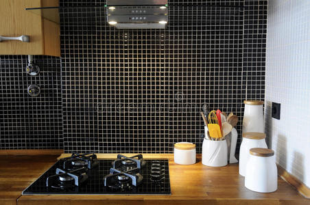 厨房有黑色瓷砖和木制柜台，天然台面，家用炉灶