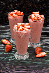 黑色和银色背景，选择性聚焦在眼镜上的新鲜草莓酸奶 牛奶和草莓奶昔装饰