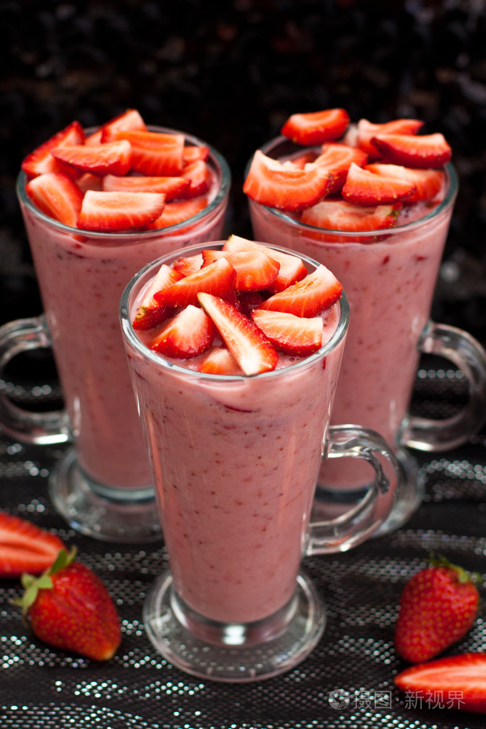 黑色和银色背景选择性聚焦在眼镜上的新鲜草莓酸奶牛奶和草莓奶昔装饰