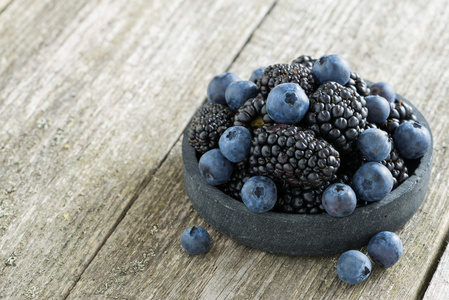 碗新鲜黑莓和蓝莓木制背景