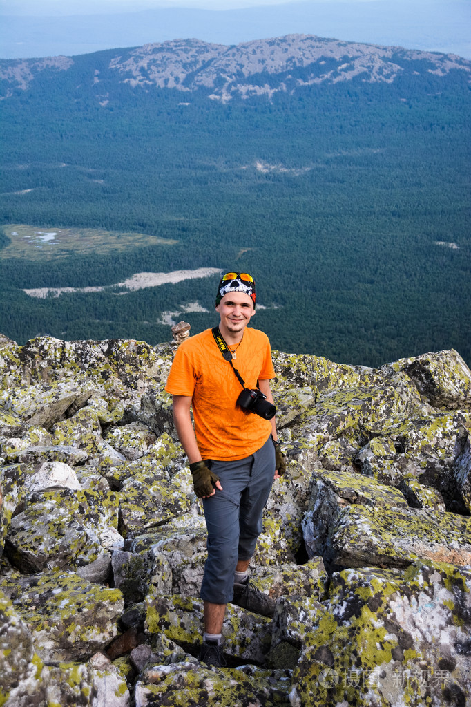 年轻英俊的男人站在一座山的顶上