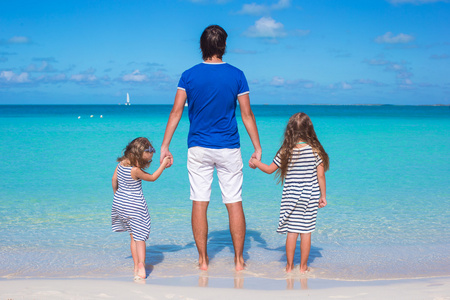 父亲和他两个孩子在海边散步图片