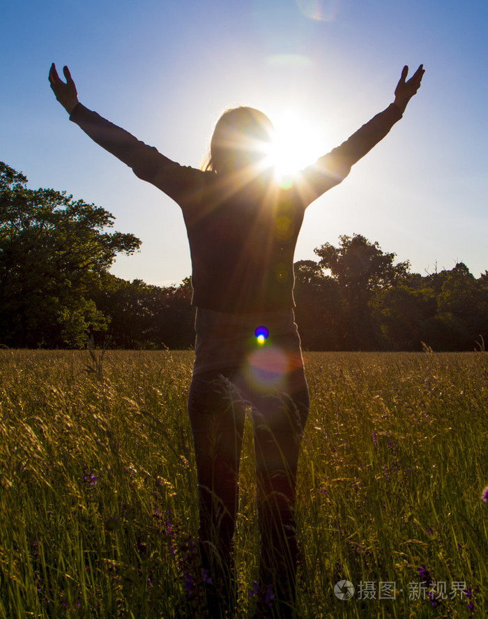 年轻的女孩传播与欢乐和灵感迎着太阳手太阳问候