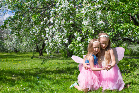 小可爱女孩与蝴蝶的翅膀在花朵盛开的苹果树下