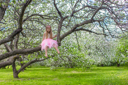 在花朵盛开的苹果树上的小可爱女孩