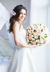 美丽的新娘模型与完美的化妆和头发风格，在明亮的房间，在一个早晨的肖像