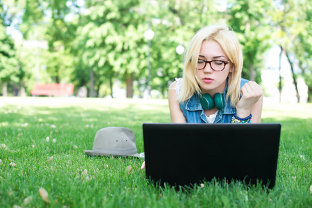 有魅力的女人使用笔记本电脑在公园说谎
