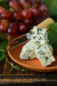 蓝纹奶酪与红葡萄在一张小木桌上的碎片