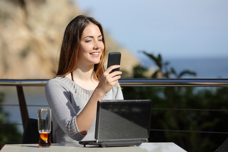 在一家餐厅与一台电脑和手机上的幸福的女人