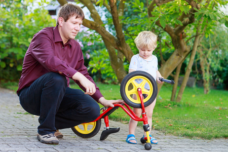 修理自行车车轮与父亲的两个小兄弟男孩